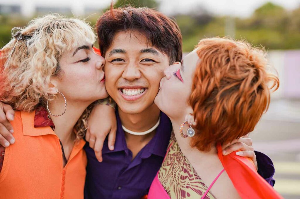 Young diverse people having fun at LGBT pride parade - Girls kissing asian boy