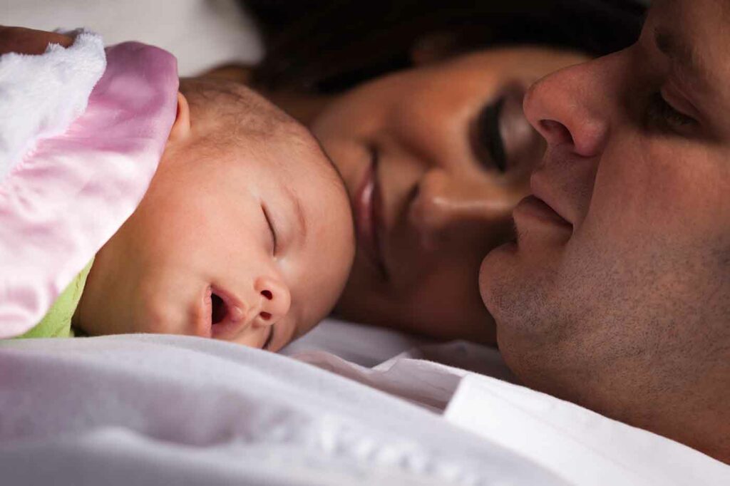 Remember Full Night Sleeps? 2 Happy Young Attractive Mixed Race Family with Newborn Baby.